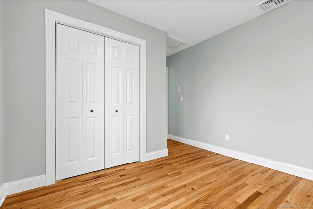 unfurnished bedroom with baseboards, light wood-type flooring, and a closet