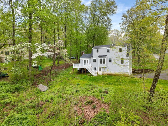 rear view of house with stairway, a deck, and a chimney