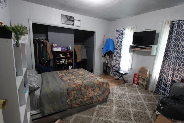 bedroom featuring wood finished floors, a closet, and a textured ceiling