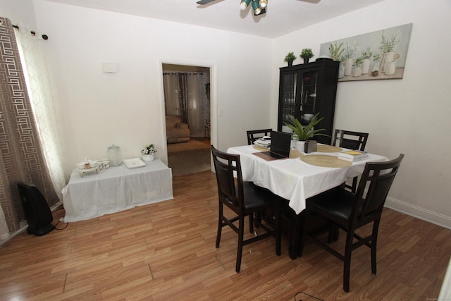 dining space featuring ceiling fan, light wood-style floors, and baseboards