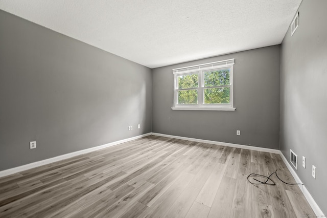 spare room featuring a textured ceiling, wood finished floors, and baseboards