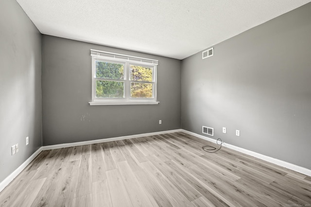 spare room featuring wood finished floors, a textured ceiling, and baseboards