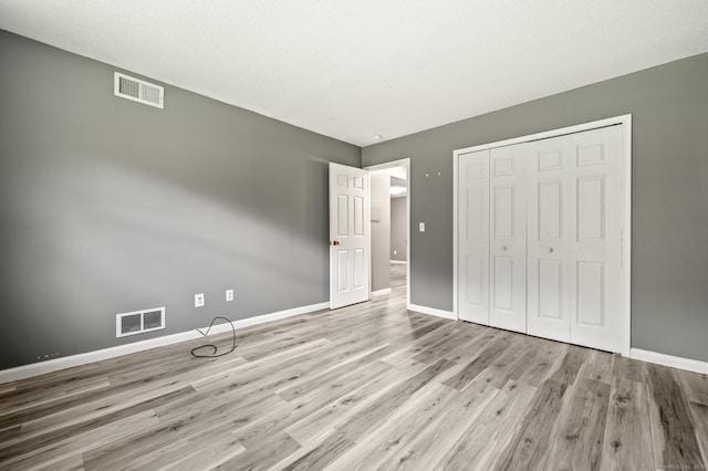 unfurnished bedroom with baseboards, wood finished floors, and a closet