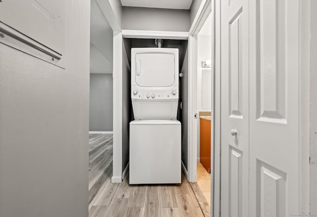 laundry room featuring stacked washing machine and dryer and light wood-type flooring