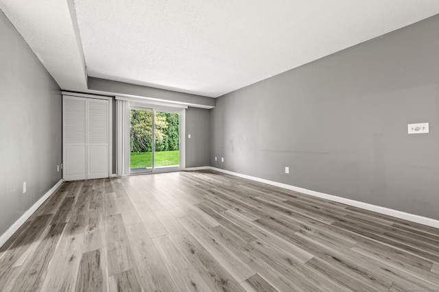 spare room featuring wood finished floors, baseboards, and a textured ceiling