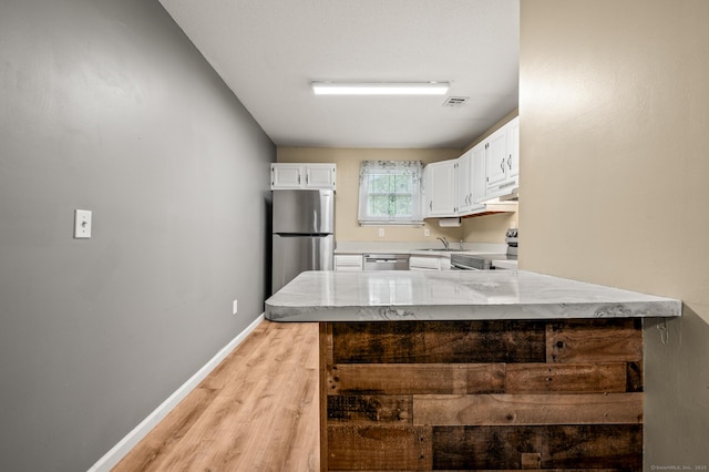 kitchen featuring appliances with stainless steel finishes, a sink, light countertops, and white cabinetry