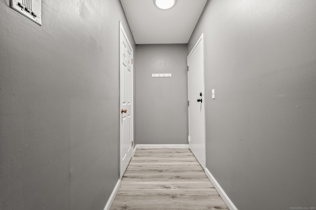 hall featuring light wood-style flooring and baseboards