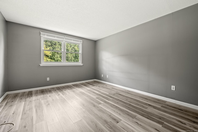 empty room featuring wood finished floors, a textured ceiling, and baseboards