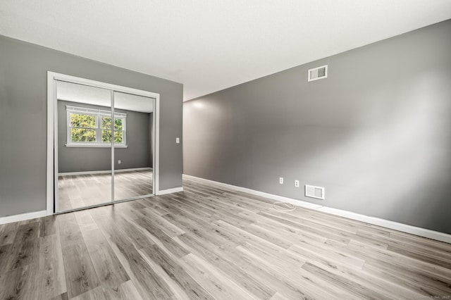 unfurnished bedroom featuring light wood-type flooring, a closet, and baseboards