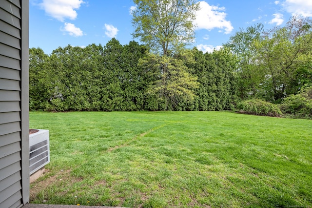 view of grassy yard with central AC
