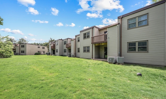 back of house featuring a lawn, central AC, and a residential view