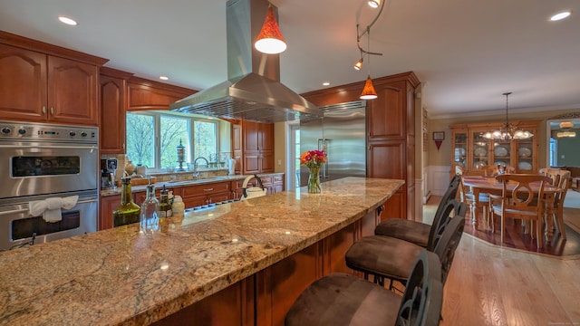 230 Ball Pond Rd, New Fairfield, CT 06812 - kitchen with stainless steel appliances, ornamental molding, a chandelier, island range hood, and light stone countertops