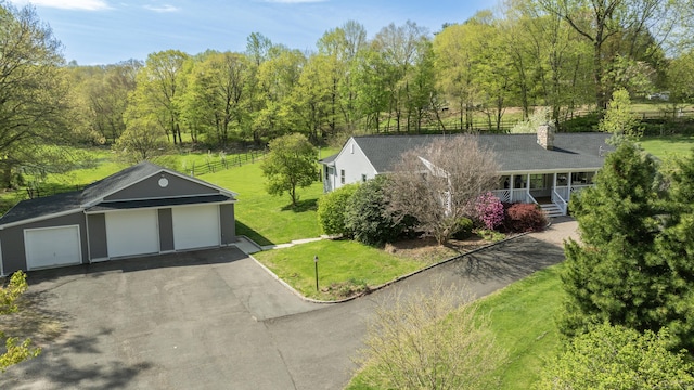 view of front of house featuring a front lawn, a chimney, an outdoor structure, and covered porch