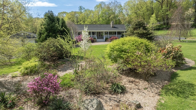 rear view of house featuring a yard, a chimney, and a porch