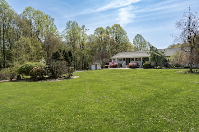 view of grassy yard with a porch, an outbuilding, and a garage