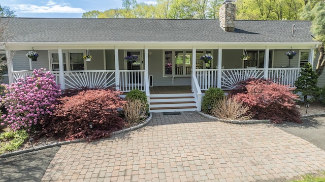 view of front facade with a porch, a chimney, and a shingled roof