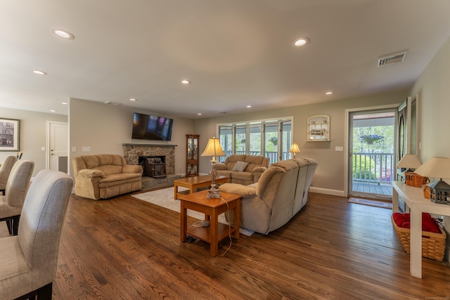 living area with dark wood finished floors, recessed lighting, a stone fireplace, and baseboards