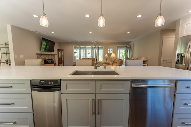 kitchen featuring stainless steel dishwasher, open floor plan, a sink, recessed lighting, and light countertops
