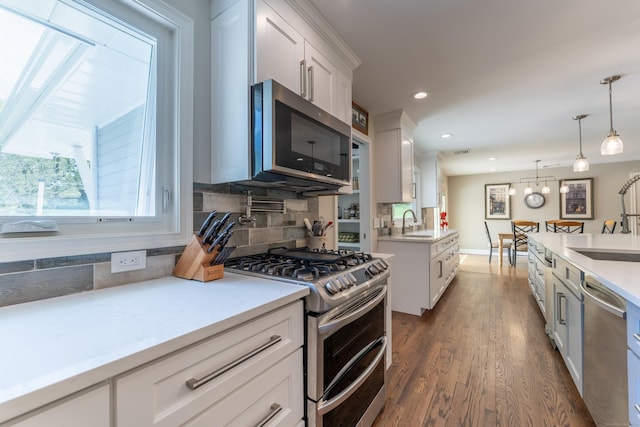kitchen with appliances with stainless steel finishes, a sink, decorative backsplash, white cabinets, and recessed lighting
