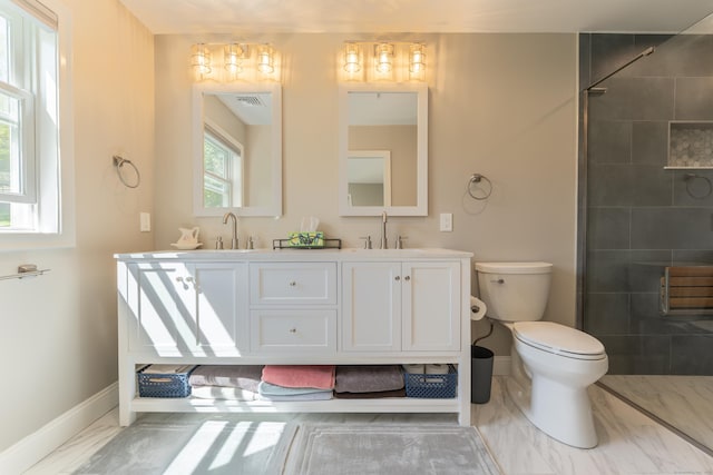 bathroom featuring baseboards, toilet, a sink, a tile shower, and double vanity