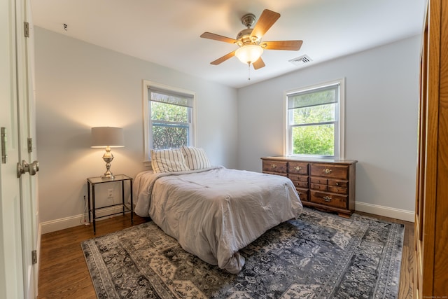 bedroom with multiple windows, baseboards, wood finished floors, and a ceiling fan