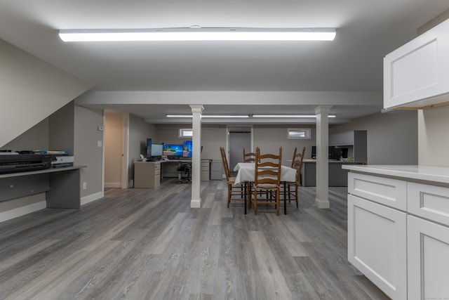 dining area featuring wood finished floors, baseboards, and ornate columns
