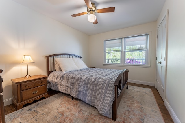 bedroom featuring baseboards, wood finished floors, and a ceiling fan