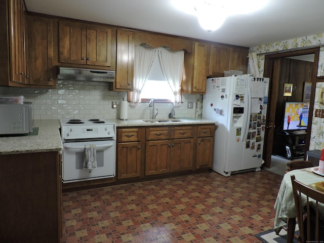 kitchen featuring a sink, white appliances, under cabinet range hood, light countertops, and tasteful backsplash