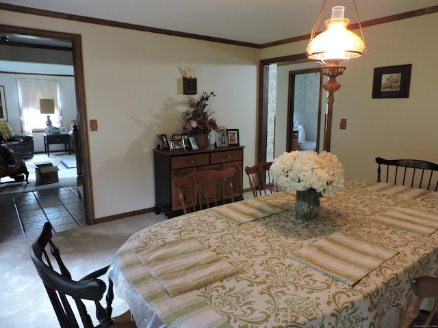 dining space with baseboards, crown molding, and carpet