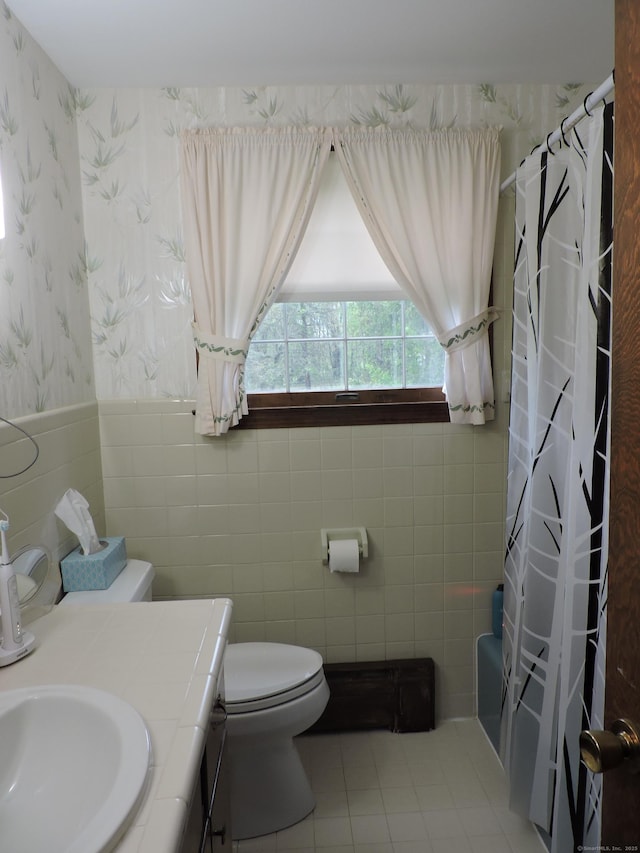 full bathroom with toilet, wallpapered walls, tile walls, wainscoting, and vanity