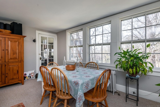dining room featuring plenty of natural light, light colored carpet, and radiator