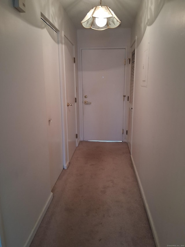 hall featuring light carpet and baseboards