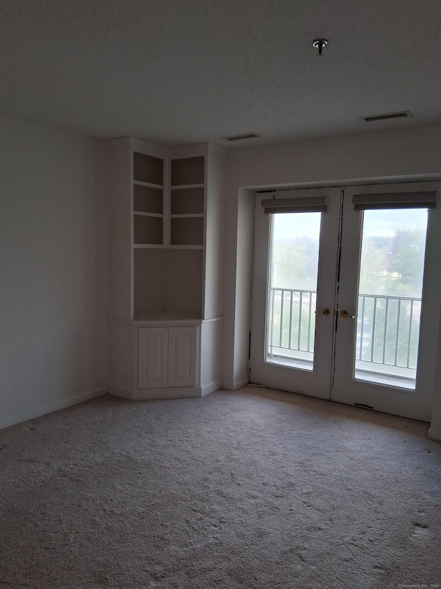 carpeted spare room with french doors, baseboards, and a pendent fire sprinkler