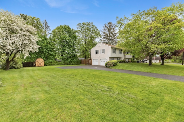 view of grassy yard featuring an attached garage, a storage shed, driveway, and an outbuilding