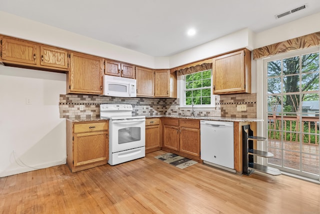 kitchen with white appliances, a sink, light wood finished floors, and decorative backsplash