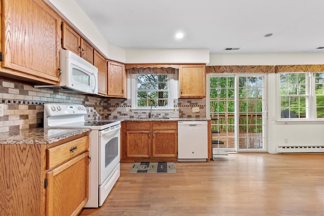 kitchen featuring white appliances, a sink, baseboard heating, light wood-style floors, and decorative backsplash