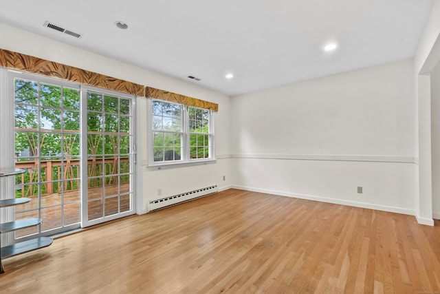 spare room featuring a baseboard heating unit, wood finished floors, baseboards, and recessed lighting