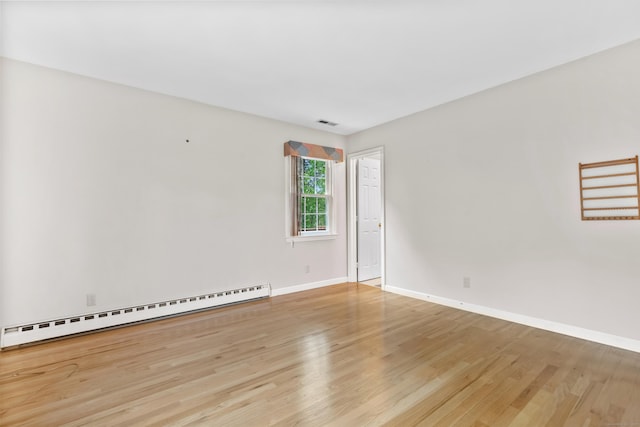spare room with baseboard heating, wood finished floors, and baseboards