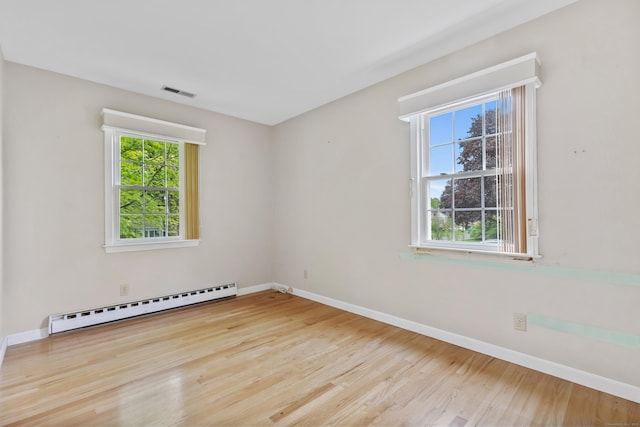 empty room with baseboard heating, baseboards, and wood finished floors