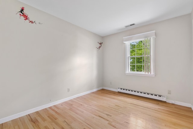 unfurnished room featuring baseboard heating, wood finished floors, and baseboards