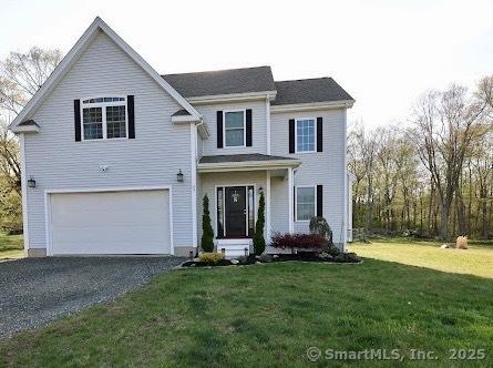 traditional-style home featuring an attached garage, a front lawn, and driveway