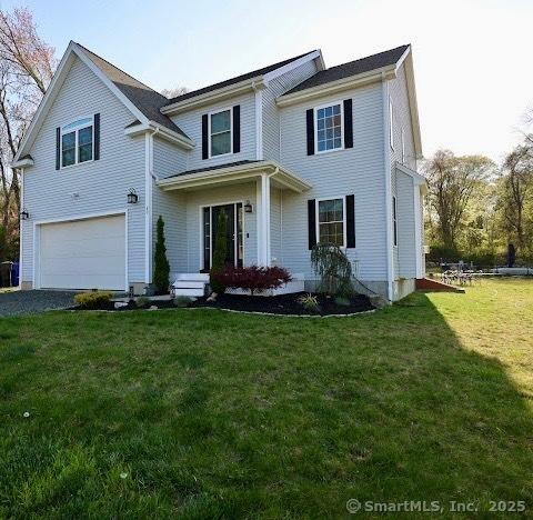 traditional home featuring an attached garage, driveway, and a front yard