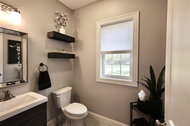 half bathroom featuring toilet, baseboards, vanity, and tile patterned floors