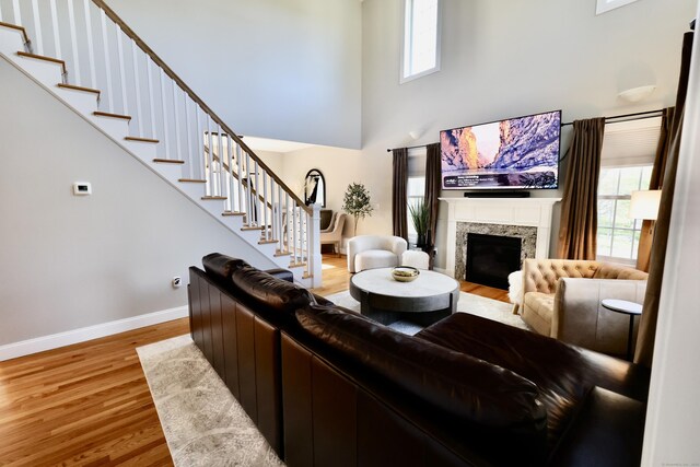 living area with a high ceiling, plenty of natural light, wood finished floors, stairway, and baseboards