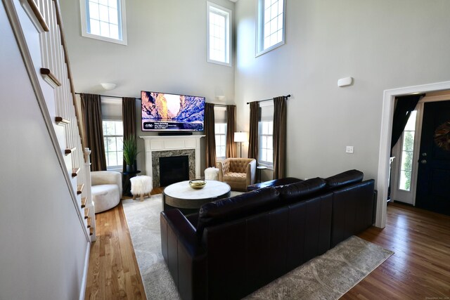 living area featuring a towering ceiling, a high end fireplace, wood finished floors, and stairway