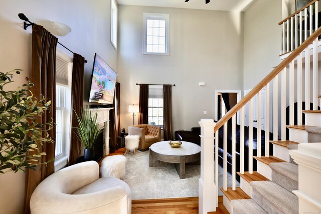 living room with a towering ceiling, stairs, wood finished floors, and a fireplace