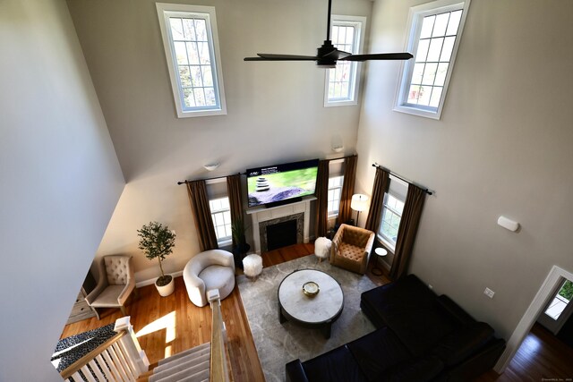living area featuring a high ceiling, wood finished floors, a high end fireplace, healthy amount of natural light, and baseboards