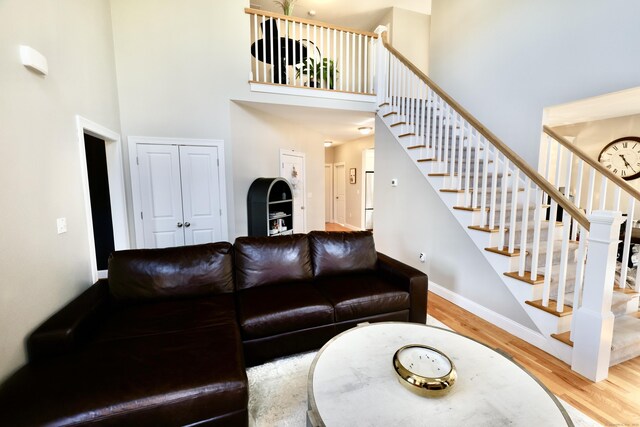 living area with a high ceiling, wood finished floors, stairs, and baseboards