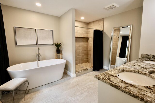 full bathroom featuring a shower stall, a freestanding tub, double vanity, recessed lighting, and baseboards