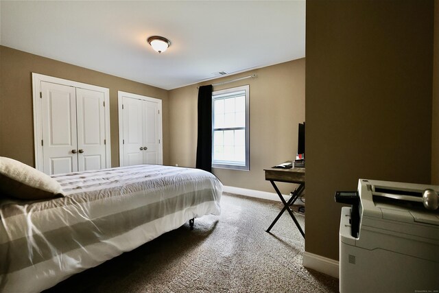 carpeted bedroom featuring baseboards and multiple closets